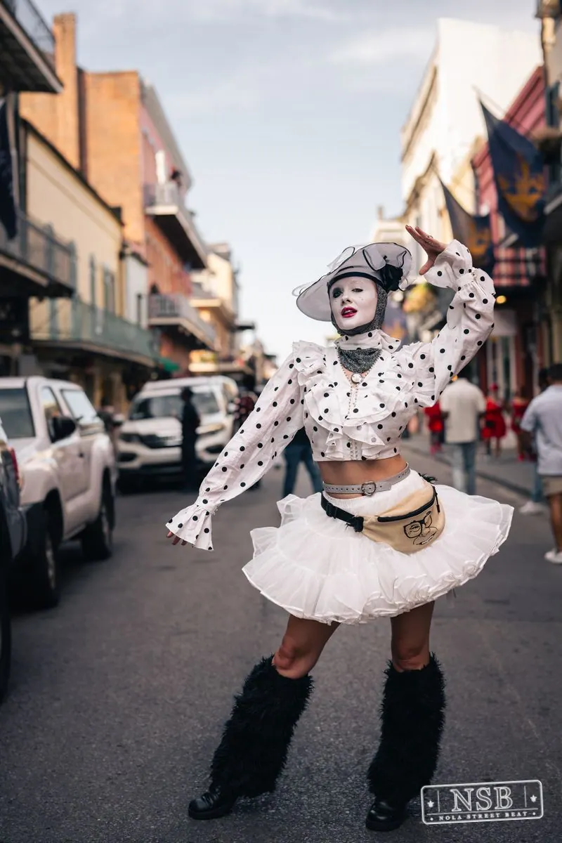 Costumed performer in a white polka-dot outfit on Royal Street at Dirty Linen Night 2026