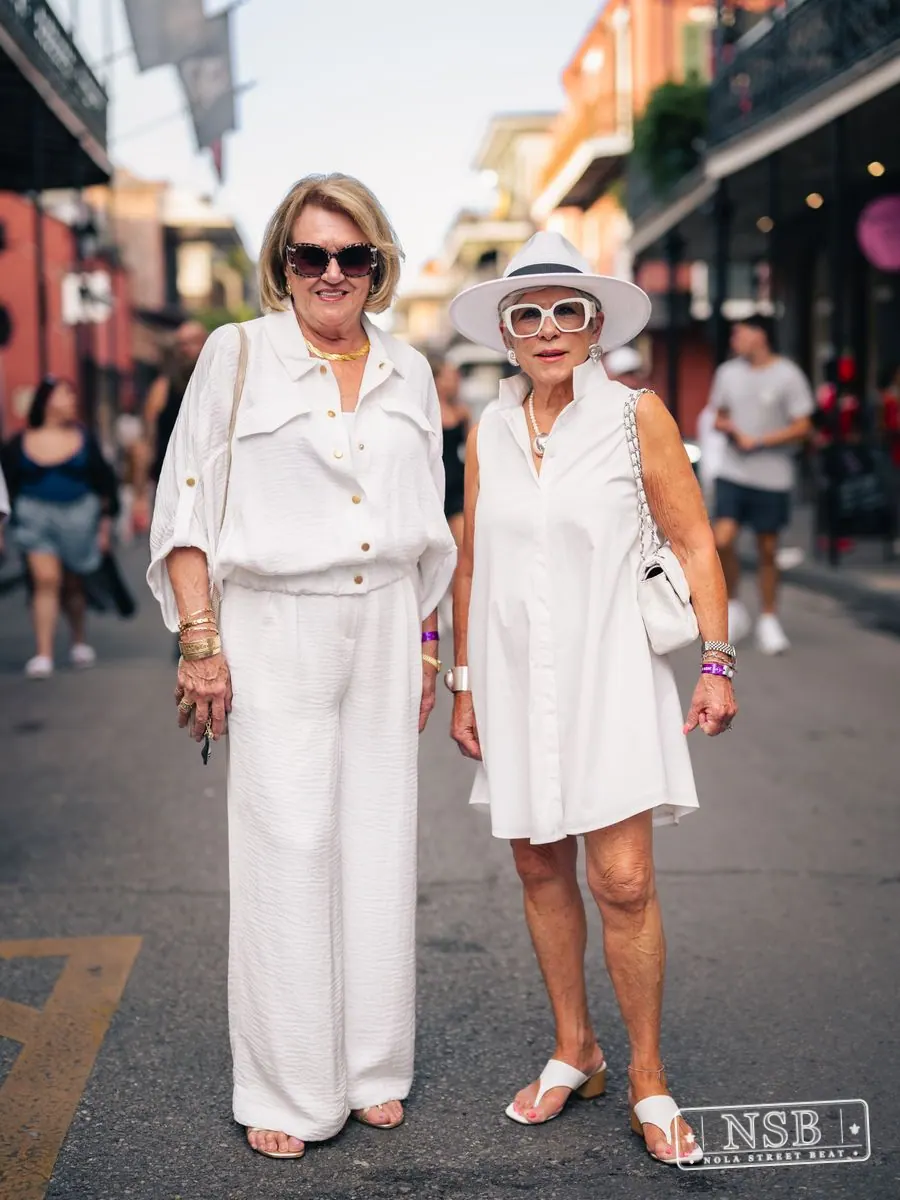 Two women dressed in white linen on Royal Street at Dirty Linen Night 2026