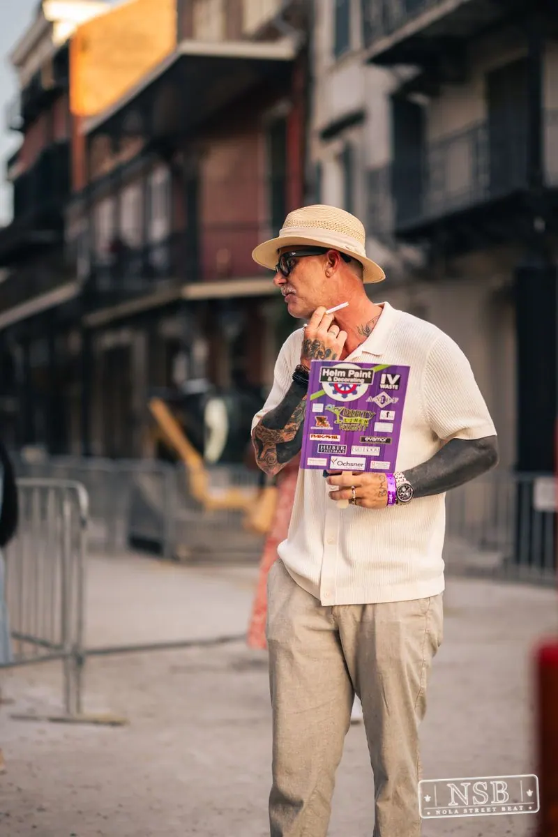 Festivalgoer holding an event flyer on Royal Street during Dirty Linen Night 2026