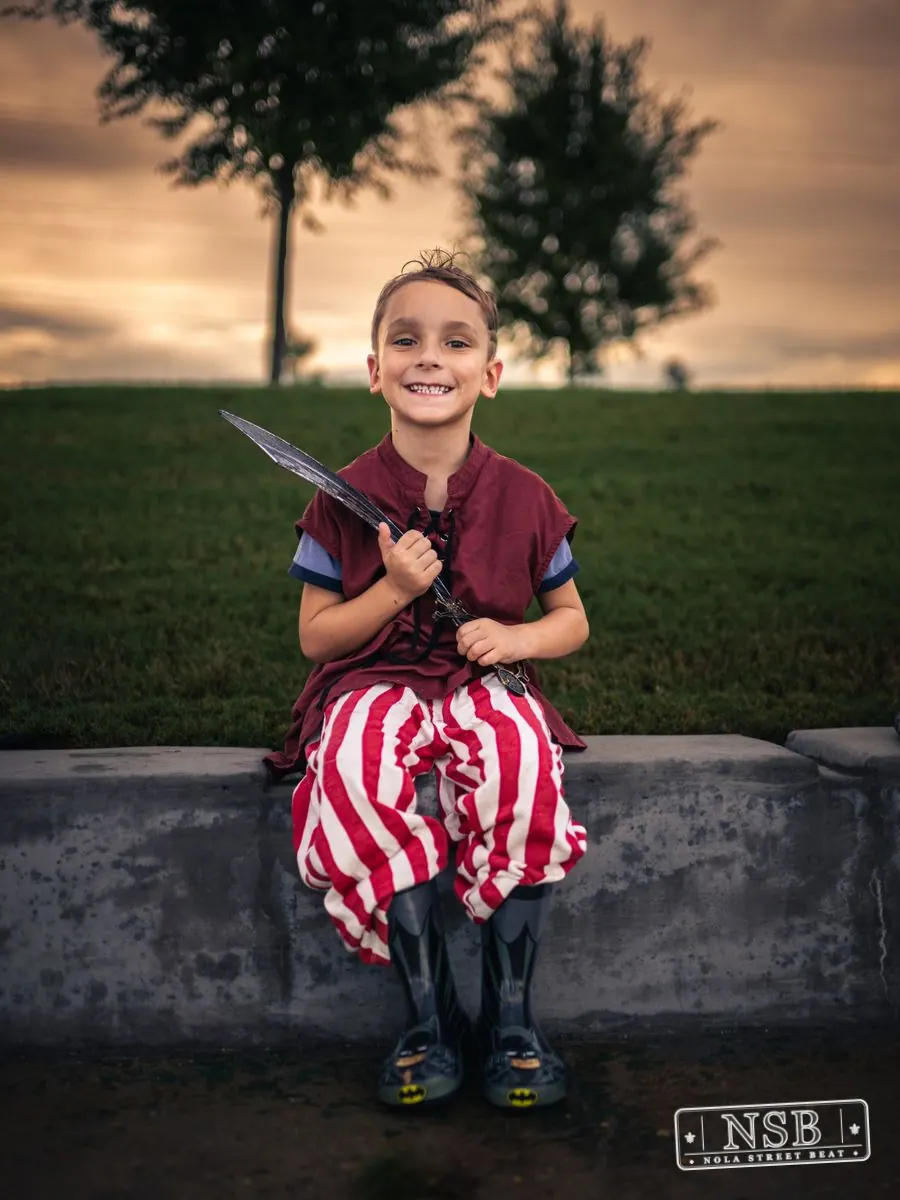 A young parade participant in a red-and-white sea-inspired costume at the 2026 New Orleans Mermaid Parade