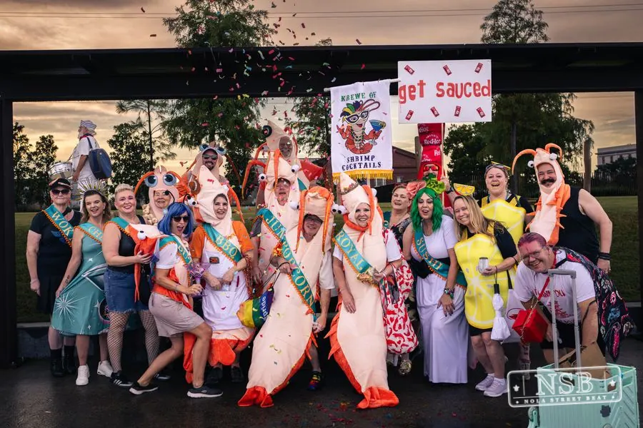 A colorful group of sea-themed parade participants posing beneath a pavilion at the 2026 New Orleans Mermaid Parade