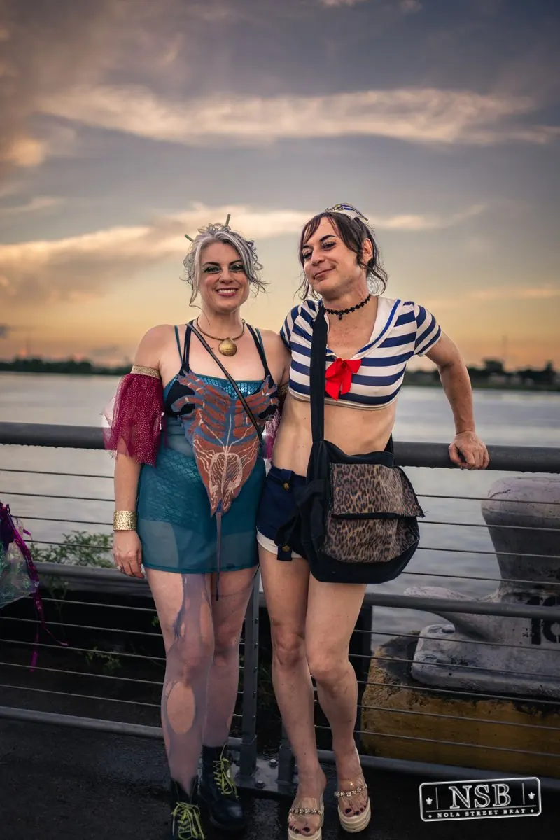 Two parade participants posing together beside the river at the 2026 New Orleans Mermaid Parade
