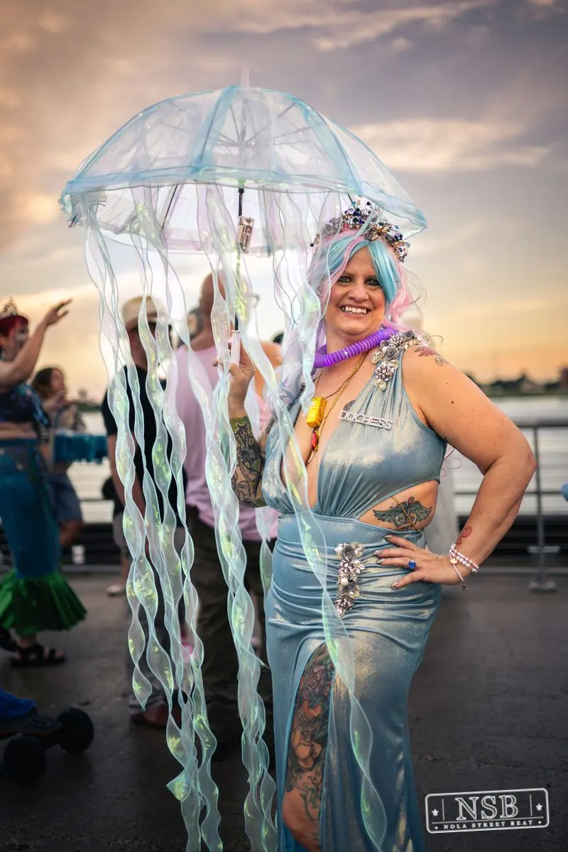 A participant beneath a translucent jellyfish umbrella at the 2026 New Orleans Mermaid Parade