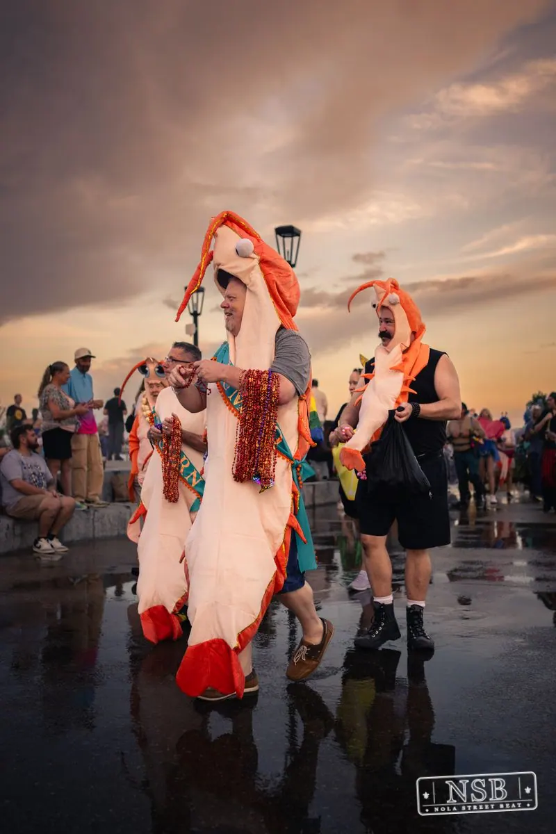 A participant in a flowing red-and-white costume along the promenade at the 2026 New Orleans Mermaid Parade