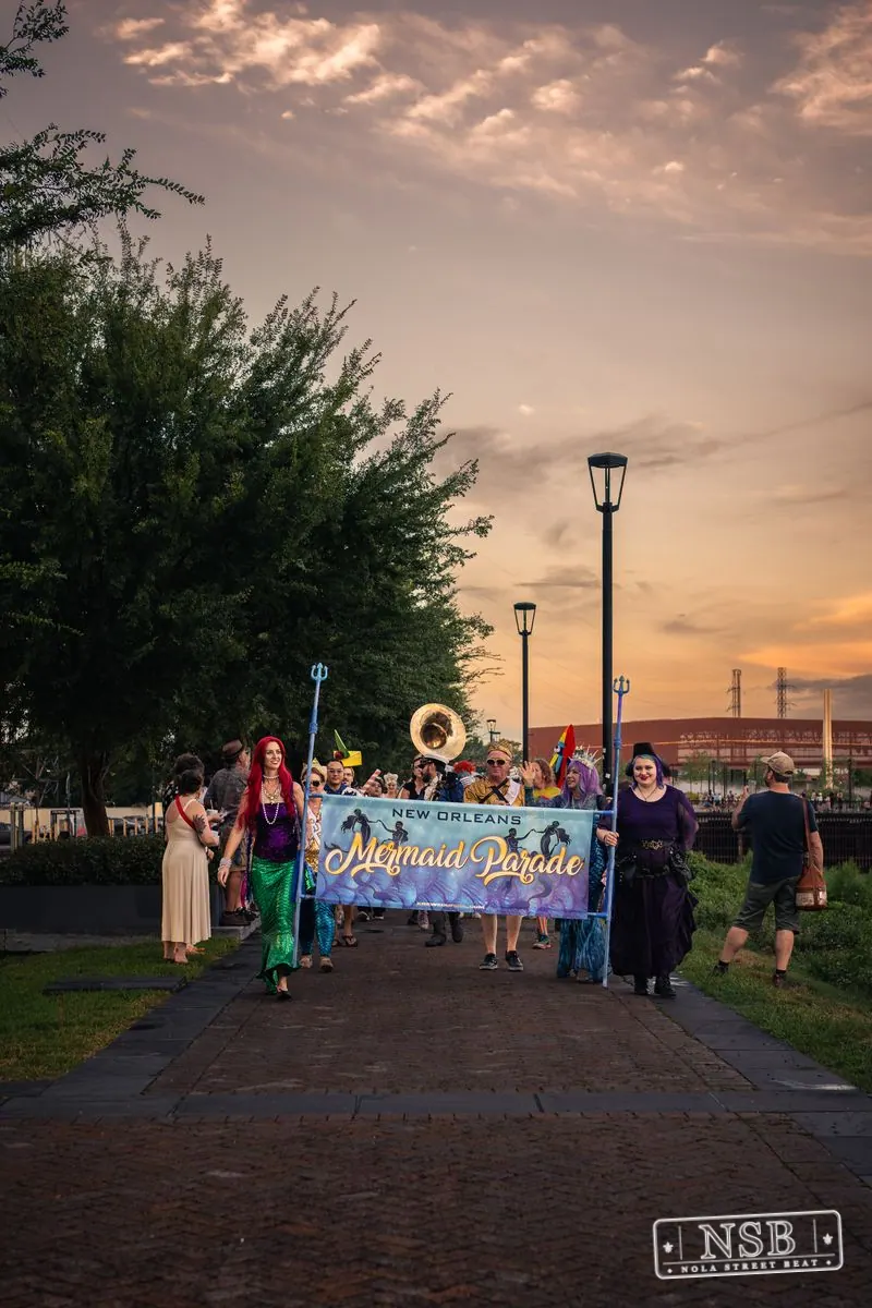 The Mermaid Parade approaching along a tree-lined path at the 2026 New Orleans Mermaid Parade