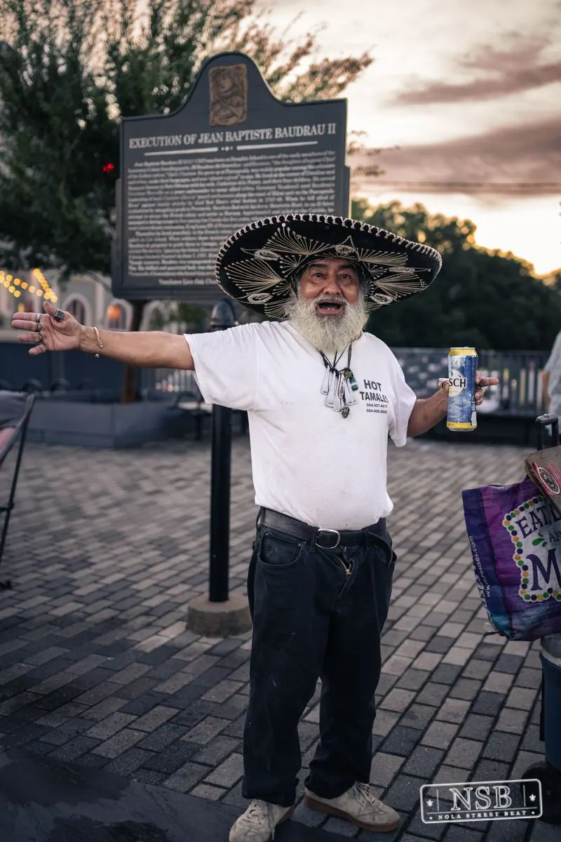 A participant in a broad hat and white shirt dancing along the parade route at the 2026 New Orleans Mermaid Parade