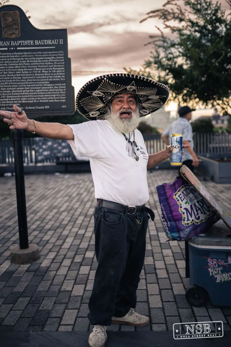 A participant in a broad hat and white shirt dancing along the parade route at the 2026 New Orleans Mermaid Parade