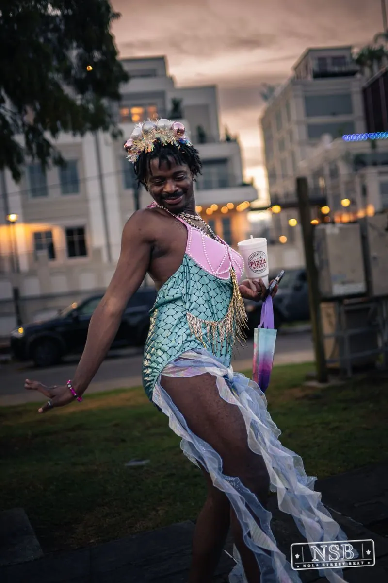 A participant in a pastel mermaid costume dancing along the route at the 2026 New Orleans Mermaid Parade