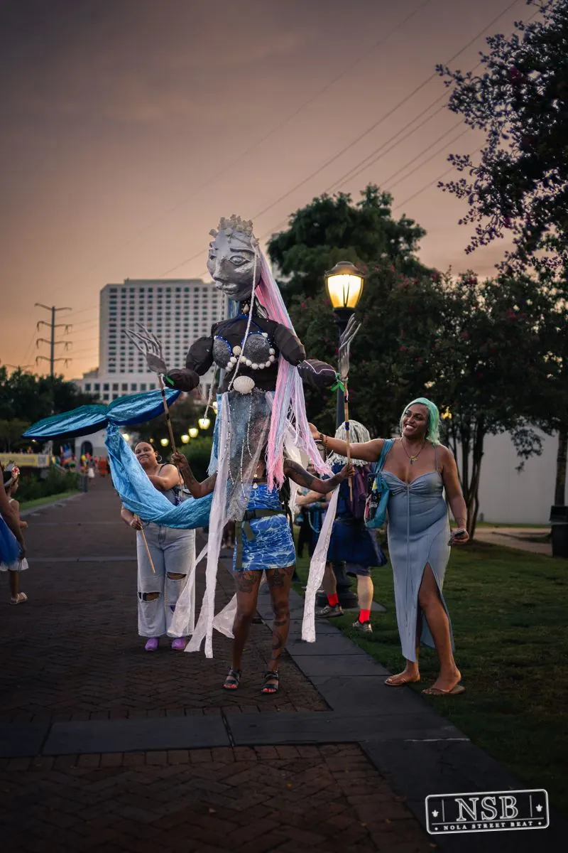 A tall sea-creature puppet moving among Mermaid Parade participants at the 2026 New Orleans Mermaid Parade