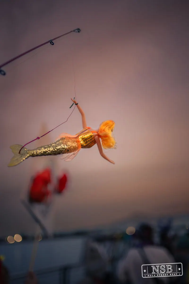 A small orange sea-creature decoration suspended above the parade at the 2026 New Orleans Mermaid Parade