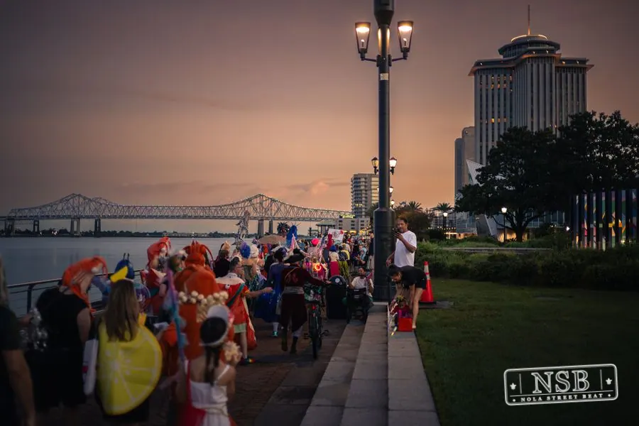 The Mermaid Parade continuing toward the Aquarium along the river at dusk at the 2026 New Orleans Mermaid Parade