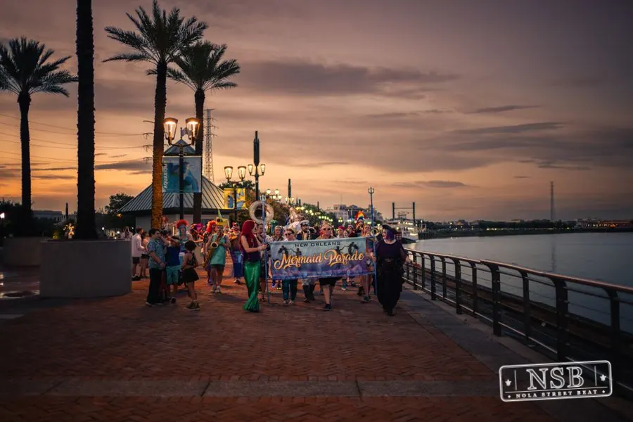 The Mermaid Parade continuing toward the Aquarium along the river at dusk at the 2026 New Orleans Mermaid Parade