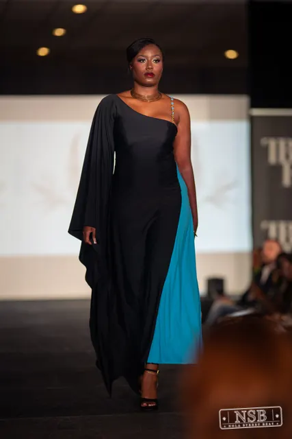 Draped black dress with turquoise panel on the runway at New Orleans Fashion Week 2026. Photo 0042 by Nola Street Beat.