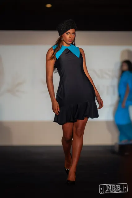 Black mini dress with turquoise collar on the runway at New Orleans Fashion Week 2026. Photo 0055 by Nola Street Beat.
