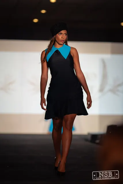 Black mini dress with turquoise collar on the runway at New Orleans Fashion Week 2026. Photo 0058 by Nola Street Beat.